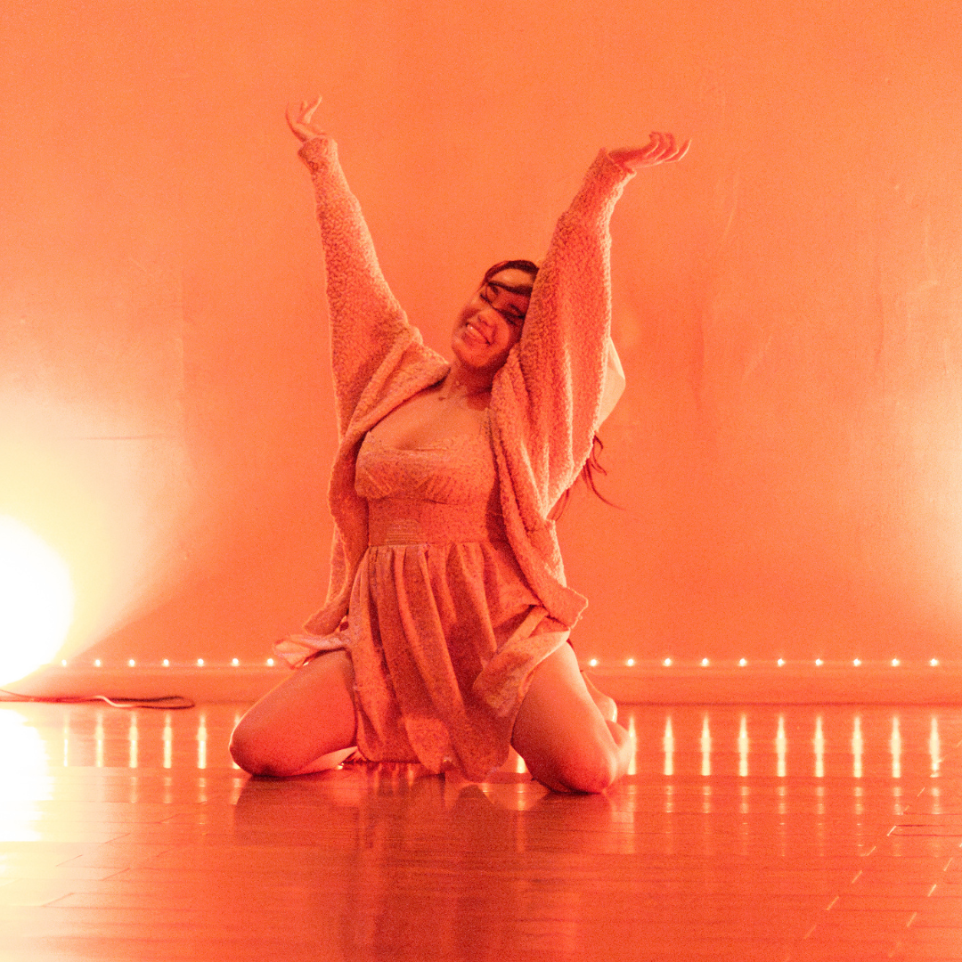 A student kneeling with arms raised in joy
